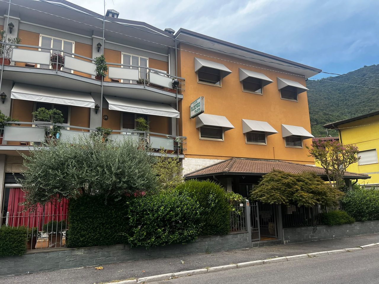 L'Albergo Milena visto dalla via, con l'insegna e la montagna dietro